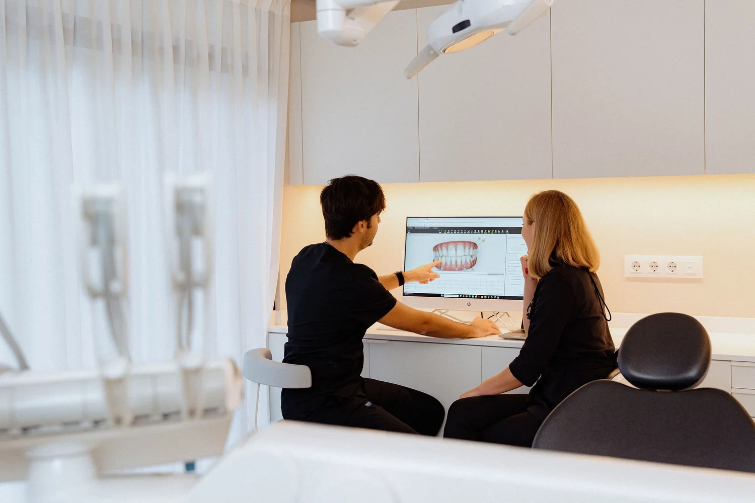 Smitasmile Barcelona dental clinic with experienced female dentist and male assistant providing treatment to patient on dental chair, all wearing professional scrubs and safety masks